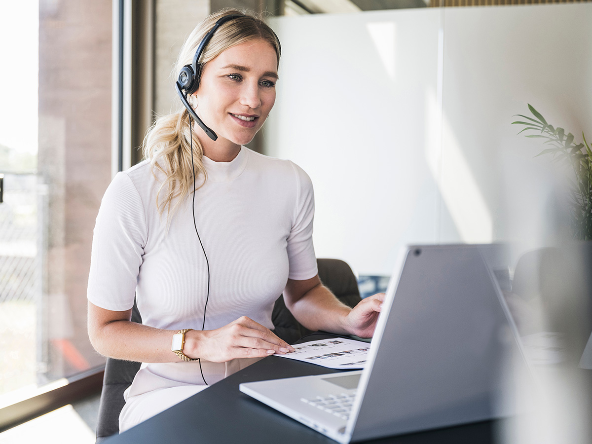 Frau mit Headset vor Laptop